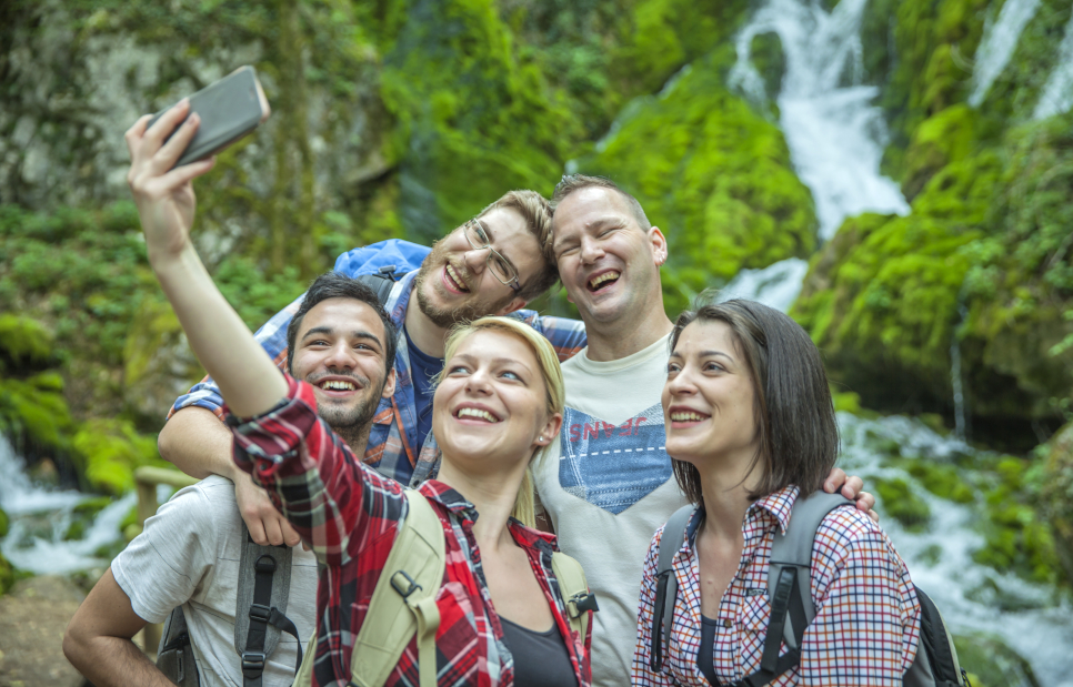 group of friends having fun and taking selfies in nature